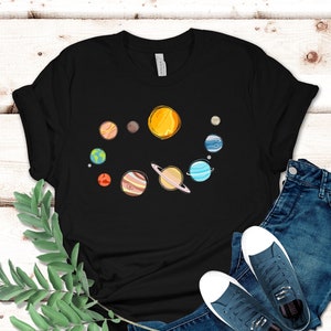May include: A black t-shirt with a graphic of the solar system. The sun is yellow, the planets are different colors, and there are rings around Saturn.
