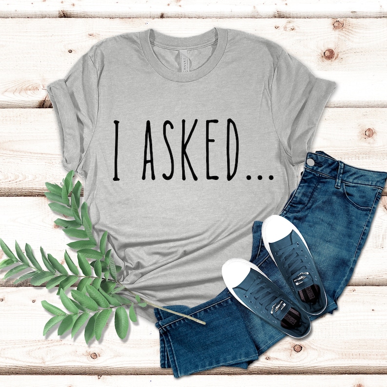 K&ouml;nnte beinhalten: Ein hellgraues T-Shirt mit dem Aufdruck "I ASKED..." in Schwarz.