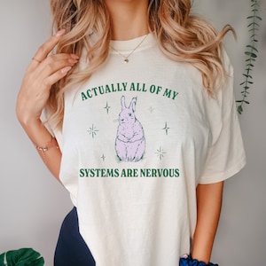 May include: A white t-shirt with a pink bunny illustration and the text "Actually all of my systems are nervous".
