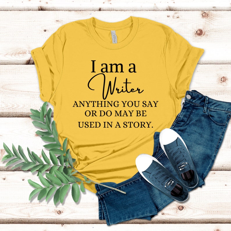 May include: A yellow t-shirt with the text "I am a Writer ANYTHING YOU SAY OR DO MAY BE USED IN A STORY."