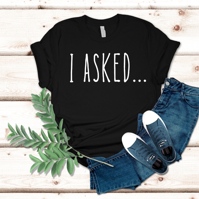 K&ouml;nnte beinhalten: Schwarzes T-Shirt mit dem Text "I ASKED..." in wei&szlig;en Buchstaben.