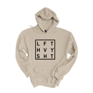 May include: A beige hooded sweatshirt with a black square graphic that says "LFT HVY SHT" in a grid pattern.