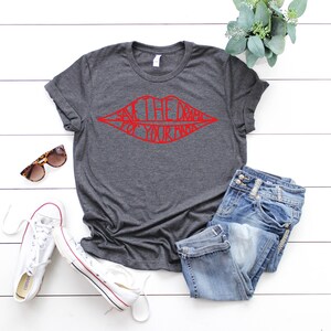 May include: A dark grey t-shirt with a red graphic of a pair of lips with the text "Save the drama for your mama" inside the lips.