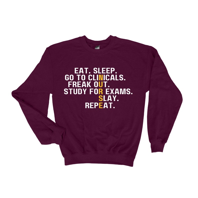 May include: Burgundy sweatshirt with the text "EAT. SLEEP. GO TO CLINICALS. FREAK OUT. STUDY FOR EXAMS. SLAY. REPEAT." in white with the word "NURSE" in yellow.