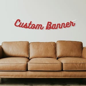 May include: Red custom banner with the text "Custom Banner" hanging above a brown leather sofa.