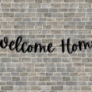 May include: Black welcome home banner hanging on a brick wall.