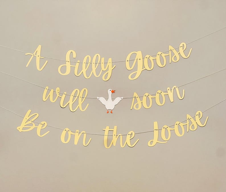 May include: A gold banner with the text "A Silly Goose Will Soon Be On The Loose" with a white goose cutout in the middle.