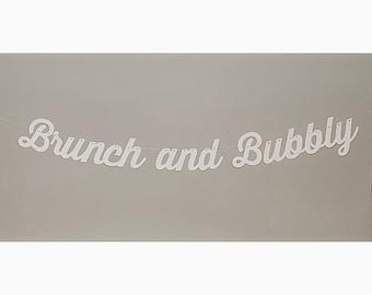 May include: White paper banner with the text "Brunch and Bubbly" in a cursive font.