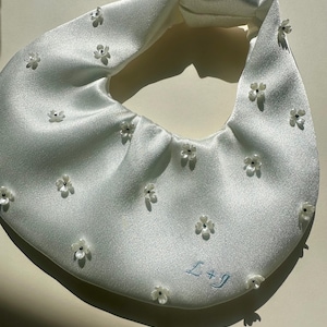 Bolso de novia de satén con flores y cuentas, ideal para ocasiones especiales, con opción de iniciales personalizadas.
