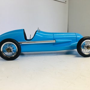 May include: A blue toy race car with chrome wheels and a single seat. The car is made of plastic and has a sleek, aerodynamic design.