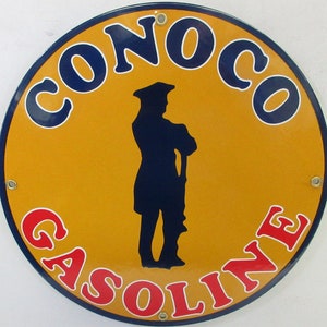 May include: A round, yellow and blue metal sign with the text "CONOCO GASOLINE" in a circle around a silhouette of a man in a colonial hat.