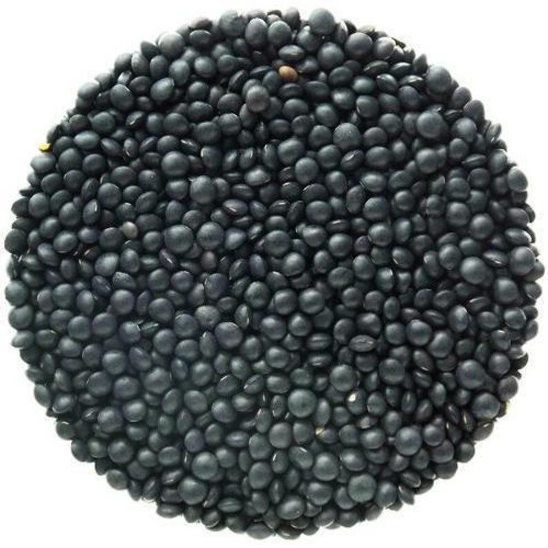 May include: A close-up view of black lentils, a type of legume, filling the entire frame. The lentils are small, round, and have a matte finish.