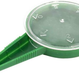 K&ouml;nnte beinhalten: Gr&uuml;ner Saatspender aus Kunststoff mit einem durchsichtigen Kunststoffdeckel. Der Deckel ist mit Markierungen f&uuml;r 1, 2, 3, 4 und 5 Samen versehen.