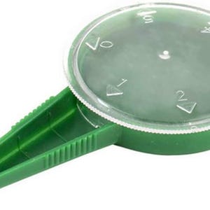 K&ouml;nnte beinhalten: Gr&uuml;ner Saatspender aus Kunststoff mit einem durchsichtigen Kunststoffdeckel. Der Deckel ist mit Markierungen f&uuml;r 1, 2, 3, 4 und 5 Samen versehen.