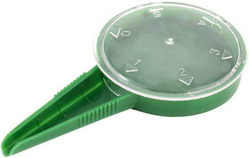 K&ouml;nnte beinhalten: Gr&uuml;ner Saatspender aus Kunststoff mit einem durchsichtigen Kunststoffdeckel. Der Deckel ist mit Markierungen f&uuml;r 1, 2, 3, 4 und 5 Samen versehen.