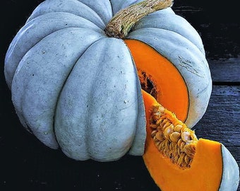 Puede incluir: Una calabaza azul pálida con una rebanada cortada, revelando la pulpa naranja y las semillas en el interior. La calabaza está sobre una superficie de madera oscura.
