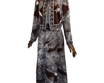 May include: A brown velvet skirt and jacket set with a white and blue floral pattern. The jacket has a gold tassel tie at the neck.