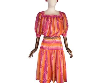May include: A vintage dress with a vibrant striped pattern in shades of orange, pink, and purple. The dress features a square neckline, short puffy sleeves, and a knee-length skirt. A gold chain belt cinches the waist, and the dress is displayed on a mannequin.