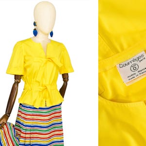 May include: A bright yellow short-sleeved jacket with a round neckline and two tie-front closures at the chest and waist. The interior label reads Courr&egrave;ges Paris, taille 0, modele depose, made in france. Paired with a multi-colored striped skirt.