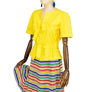 May include: A bright yellow short-sleeved blouse featuring a notched neckline with a tie detail and a cinched waist with a matching tie belt. The blouse is paired with a skirt displaying horizontal stripes in red, blue, green, and yellow colors.