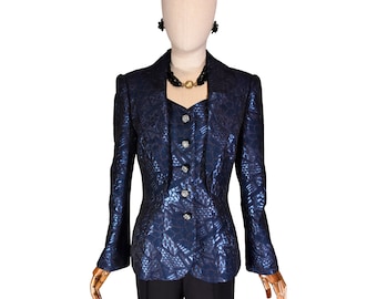 May include: A navy blue women's suit set on a mannequin. The set includes a textured blazer, a matching vest with decorative buttons, and black trousers. A black beaded necklace and earrings complete the ensemble.
