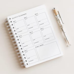 May include: A white spiral-bound outfit planner notebook with black text and grid lines. The page features sections labelled OUTFIT PLANNER, DAY 1 through DAY 7, and TO BUY / NOTES, with sub-sections for OUTFIT, SHOES, and ACCESSORIES. A clear pen is included.