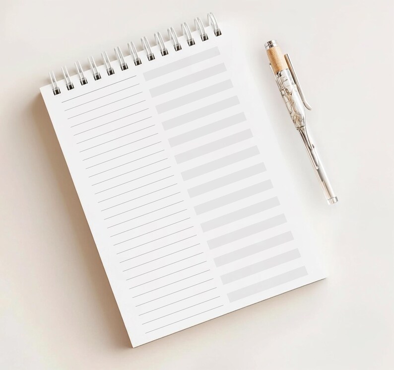 May include: A white spiral-bound notebook with lined and blank sections, and a silver pen with a wood-tone top. The notebook is open, and the pen is resting on a white surface.