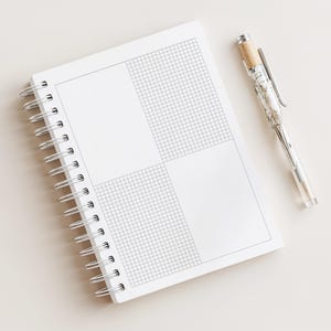 Peut inclure: Un carnet blanc à spirales avec un motif quadrillé et des sections vierges, à côté d'un stylo transparent avec un intérieur décoratif et un bouchon en liège. Le carnet est ouvert, affichant la grille et les zones vierges.