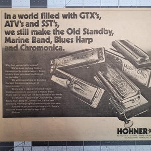 May include: A vintage advertisement for Hohner harmonicas, featuring a close-up of various harmonicas, including the Marine Band, Blues Harp, and Chromonica. The ad text reads "In a world filled with GTX's, ATV's and SST's, we still make the Old Standby, Marine Band, Blues Harp and Chromonica."