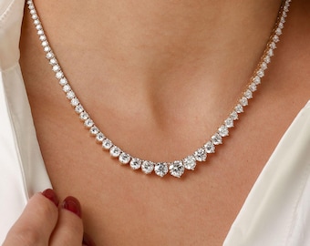 May include: A diamond necklace with a graduated design. The necklace features numerous round-cut diamonds set in a delicate, gold-toned metal. The diamonds increase in size towards the center of the necklace.