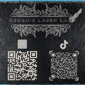 Puede incluir: Pizarra rectangular negra con texto grabado "OSCAR'S LASER LAB" y adornos decorativos. Hay cuatro códigos QR presentes, junto con iconos de Etsy, TikTok y un signo de dólar. La pizarra tiene una superficie texturizada.