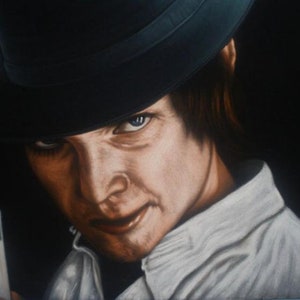 May include: A close-up portrait of a man wearing a black fedora hat and a white collared shirt. He has dark hair and a serious expression on his face. He is holding a glass of milk in his left hand.