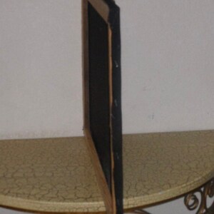 May include: A wooden picture frame with a black mat and a dark brown wood finish. The frame is standing upright on a table with a light brown surface.