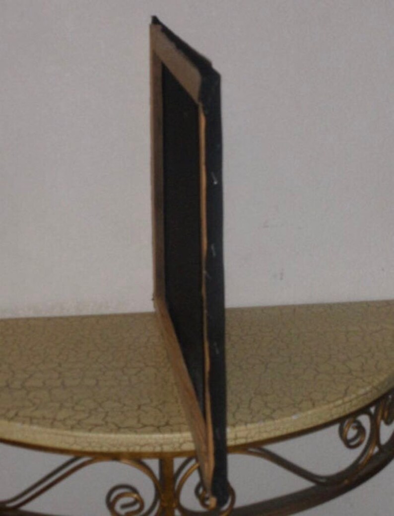 May include: A wooden picture frame with a black mat and a dark brown wood finish. The frame is standing upright on a table with a light brown surface.