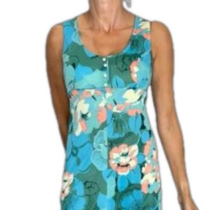 May include: Sleeveless dress with a floral pattern in shades of blue, green, peach, and white. The dress has a scoop neckline, a button-up bodice, and a fitted waist. The floral print is a mix of large and small blooms.