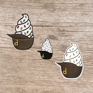 May include: Three embroidered patches of ice cream cones in different sizes. The ice cream is white with colorful sprinkles and the cones are brown with a yellow "D" on the side.