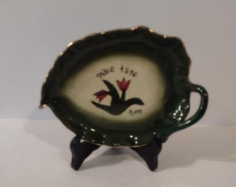 Portavelas de arcilla vintage con forma de hoja verde y borde dorado. Medidas: 18 cm de largo x 14 cm de ancho.