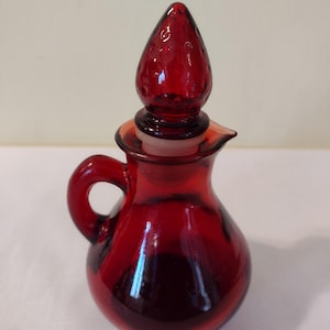 Vintage Avon Decanter Bottle. Ruby Red Glass With Strawberry Stopper. Size 5.5&quot; Hight, 9&quot; Wide.