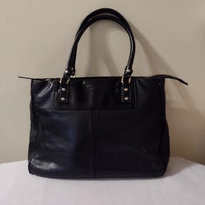 May include: Black leather tote bag with gold hardware and a zip closure.
