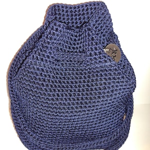 Op de afbeelding: Een marineblauwe gehaakte trekkoordtas met een textuurpatroon. De tas heeft een afgeronde vorm met een handvat en een klein, rond label. De tas is gemaakt van een geweven materiaal en lijkt een schoudertas of handtas te zijn.