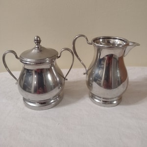 Vintage set of sugar & creamer. Color silver. Size Sugar 4&quot; Tall, Creamer 5&quot; Tall. Handmade In U.S.A.