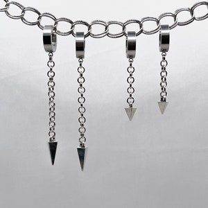 May include: Four silver chain earrings with a triangle pendant at the end of each chain. The chains are attached to a silver hoop.