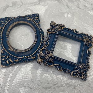 May include: Two ornate picture frames with gold accents. The frames are blue and have a decorative design.