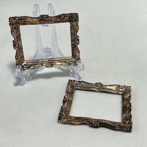 Könnte beinhalten: Zwei verzierte goldene Bilderrahmen mit einem dekorativen, verzierten Design. Die Rahmen sind leer und bereit, Ihre Lieblingsfotos oder Kunstwerke zu präsentieren.