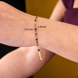 K&ouml;nnte beinhalten: Ein filigranes goldenes Armband mit kleinen, runden und ovalen Gliedern. Das Armband wird an einem Handgelenk gezeigt, mit sichtbaren Ma&szlig;en von 5,13 mm und 2,82 mm. Der Schmuck hat eine helle, gl&auml;nzende Goldfarbe.