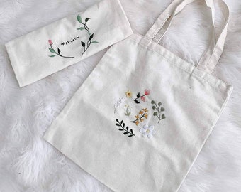 May include: Two white canvas tote bags with embroidered floral designs. One bag has the text "#minx" embroidered on it.