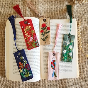May include: Set of six embroidered bookmarks with colorful floral and fish designs. Each bookmark has a tassel and a metal ring at the top.