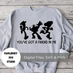 Op de afbeelding: Grijs sweatshirt met een zwart silhouet van Woody, Buzz Lightyear en Jessie uit Toy Story. De tekst "You've got a friend in me" is onder de personages gedrukt.