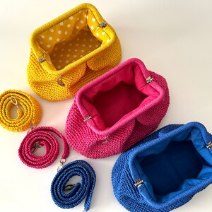 Pu&ograve; includere: Tre borsette all'uncinetto con tracolle abbinate in giallo, rosa e blu. Le borsette sono aperte e mostrano la fodera in tessuto all'interno.