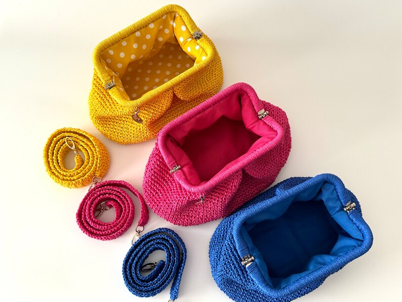 Pu&ograve; includere: Tre borsette all'uncinetto con tracolle abbinate in giallo, rosa e blu. Le borsette sono aperte e mostrano la fodera in tessuto all'interno.